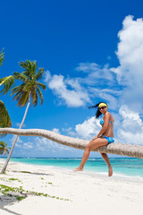 Tanned woman sitting on a palm white sand beach