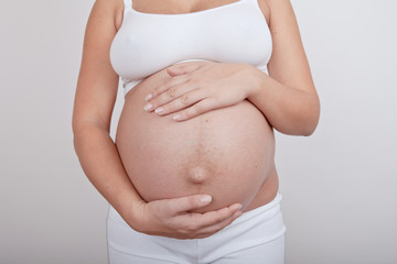 Pregnant woman hold hands on a belly