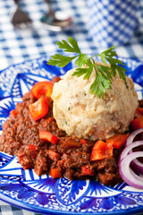 Gulasch mit Knödel auf einer blauen Teller
