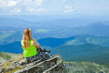 Naklejka premium Woman sitting on mountain peak