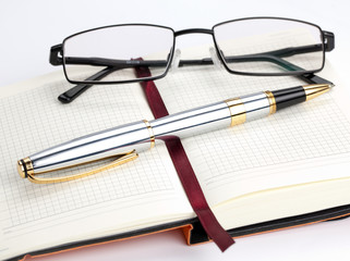 Notebook with pen and glasses