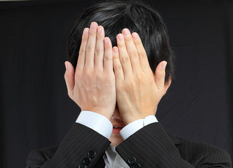 businessman covering his face by hands