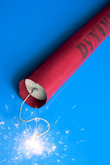 Lit dynamite stick on a blue background