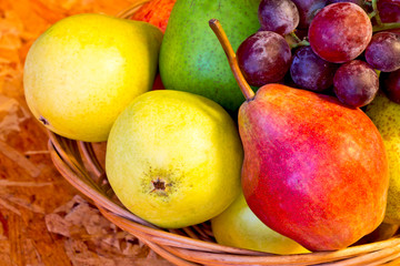 yellow, red and green pears with red grapes in woven baskets