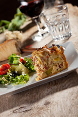 Stück Quiche Lorraine mit Salat und Wein