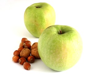 grosse mele verdi con noci e nocciole su fondo bianco