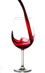 Pouring red wine into glass, isolated on white background