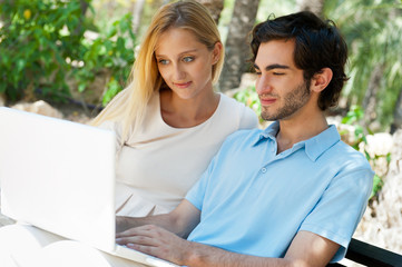 Young couple working on laptop and smiling while sitting relaxed