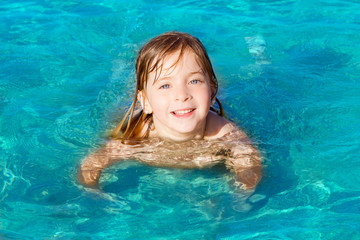 Fototapeta na wymiar blond little girl swimming in turquoise beach