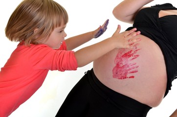A daughter is painting on her mother`s belly