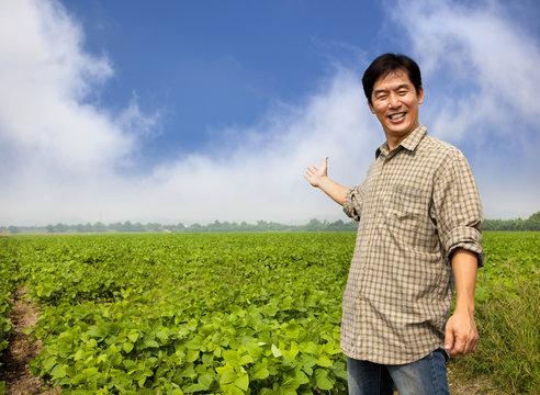 happy asian farmer showing his farm
