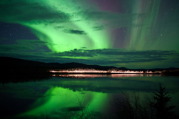 Fototapeta na wymiar Gwiazdy i Northern Lights ponad ciemną drogą, nad Jeziorem