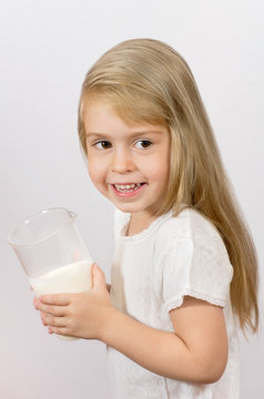 Cheerful girl holding a large glass of milk. Breakfast time.