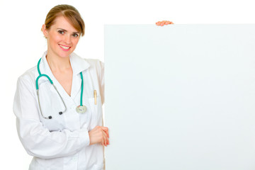 Smiling medical female doctor holding blank billboard
