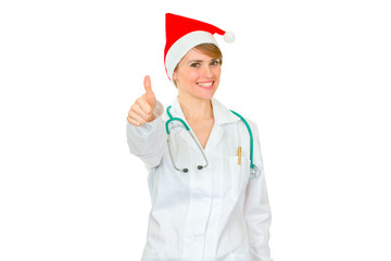 Smiling medical female doctor in Santa hat showing thumbs up