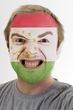 Face of crazy angry man painted in colors of Tajikistan flag
