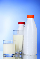 Obraz na płótnie Canvas Tasty milk in glass and bottle on blue background