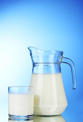 Tasty milk in jug on blue background