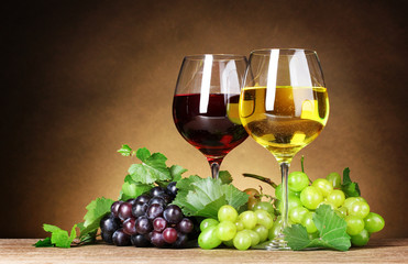 Glasses of wine and grapes on yellow background