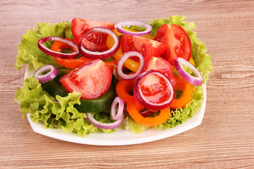 salad of fresh vegetables on the plate on wooden background