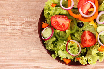 many vegetables on the plate on a wooden background
