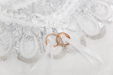 Two wedding rigns on white garter