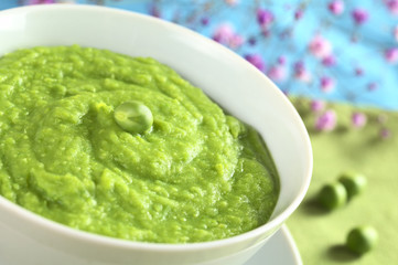 Fresh green pea soup with pea seeds beside