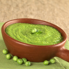 Fresh green pea soup in rustic bowl on jute with copyspace
