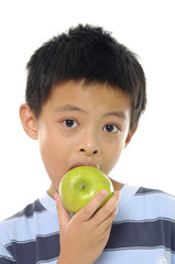 Little boy bites off apple, is isolated on white background.