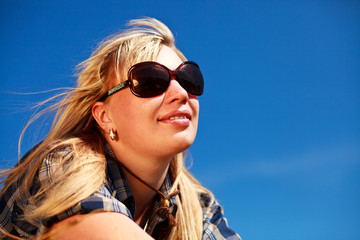 Blonde girl in skirt and sunglasses portrait on blue sky