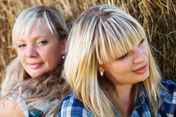 Two country girls on straw bales background.