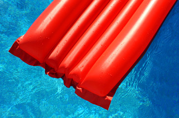 Colchoneta roja en piscina azul