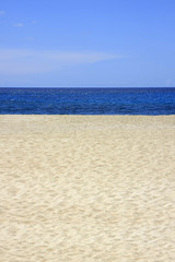 Sandstrand mit blauem Meer und Himmel im Hochformat