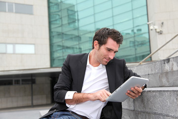 Man using electronic tablet in front of modern building