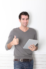 Man leaning on wall with electronic tablet