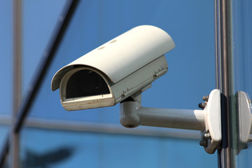 white security CCTV camera on glass facade