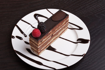 Slice of fancy chocolate cake topped on white plate