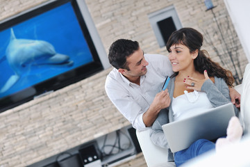 Obraz na płótnie Canvas joyful couple relax and work on laptop computer at modern home