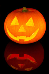 Halloween pumpkin with scary face with reflection on black glass