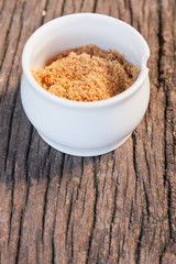 small cup of brown sugar on wood teak