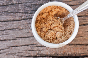 small cup of brown sugar and spoon on wood teak