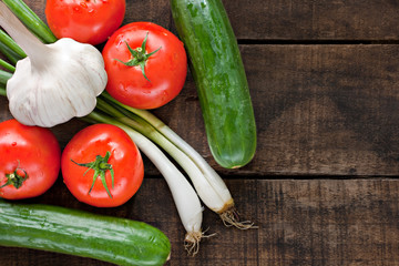 Tomatoes, cucumber, garlic and spring onions on old wooden table