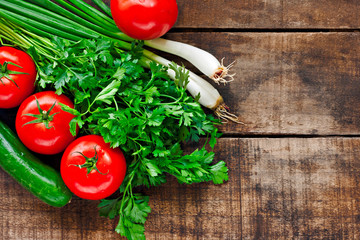 Tomatoes, cucumber, coriander and spring onions on old wooden ta