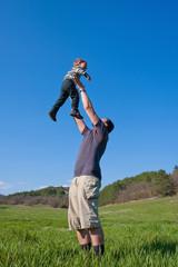 Father is playing with his 1.5 year son on the meadow