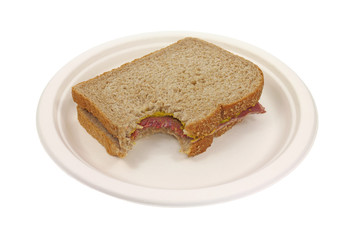 Bitten corned beef sandwich on paper plate
