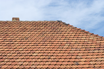 The roof of tiles and chimney against the sky.