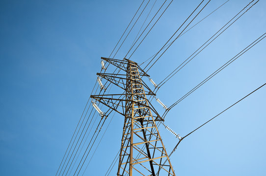 Low angle view of a tall electric power tower on a summer day with blue sky