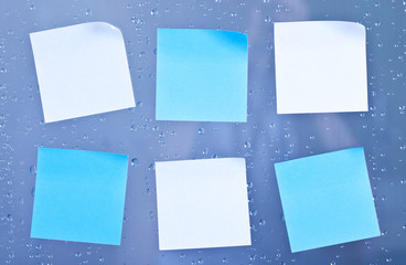 Sticky notes on a bathroom glass panel with water droplets