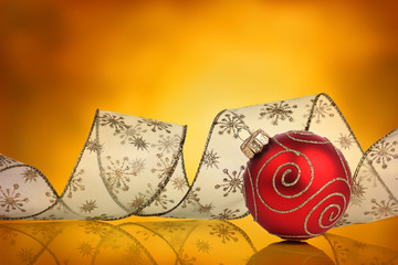 Red christmas bauble with curled ribbon and vivid background