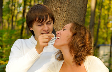 Boyfriend feeding on candy her girlfriend  in the park